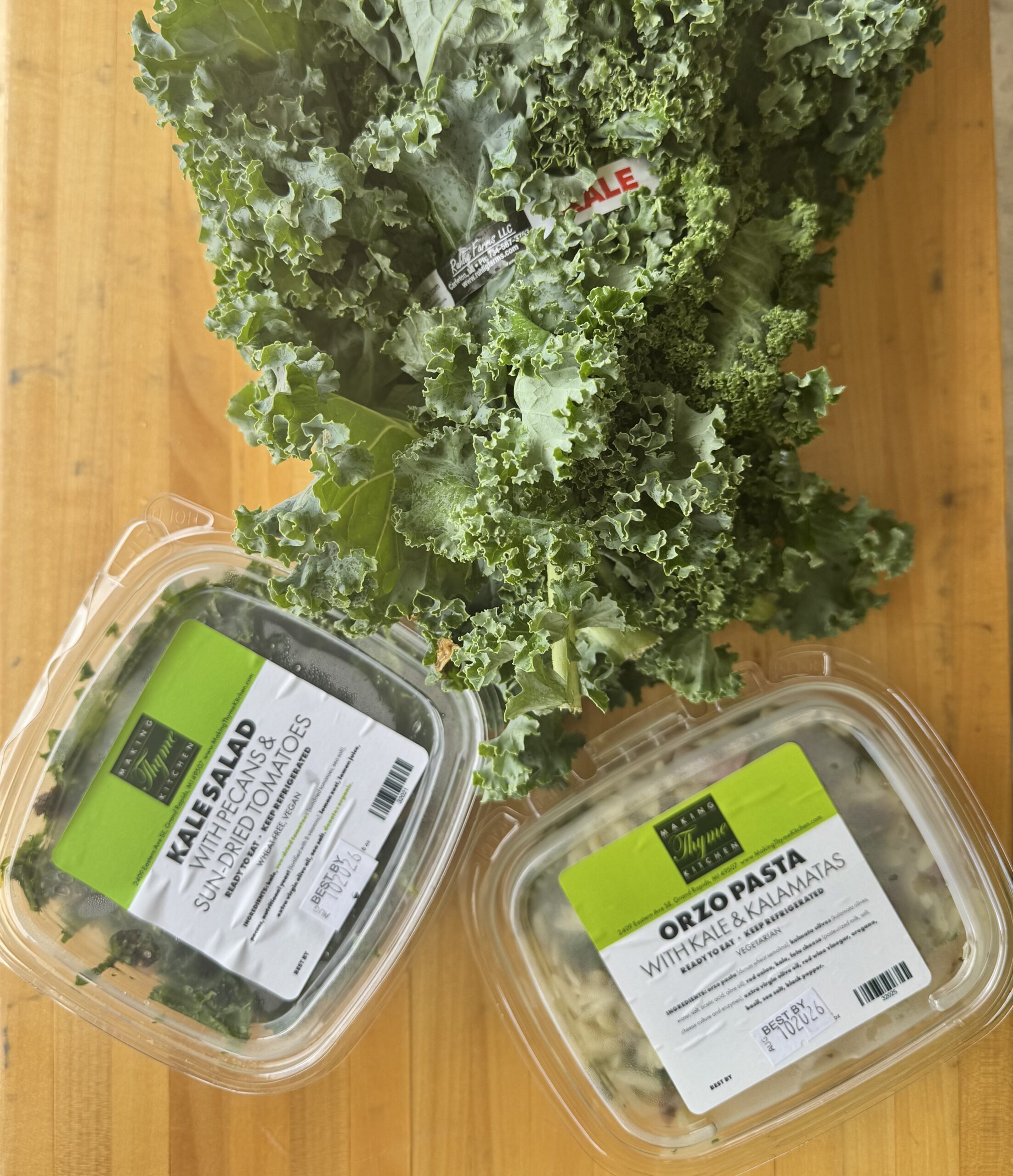 Fresh kale beside packaged deli salads